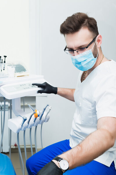 здравоохранение, профессия, стоматология и медицина концепция - улыбающийся молодой стоматолог мужского пола на медицинском фоне офиса
