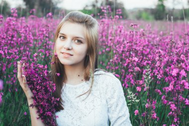 Güzel Gelin çiçek alanı. Beyaz elbiseli kız gün batımında yaz alanında bir buket ile