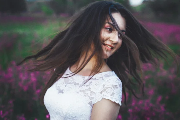 Vackra unga brud i fält, glad kvinna njuter av blommor. — Stockfoto