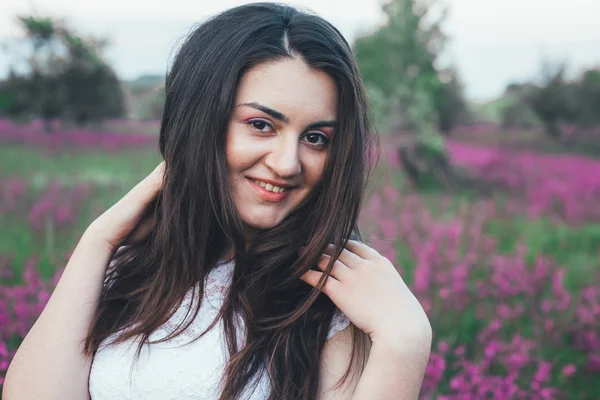 Bela noiva jovem no campo, mulher feliz apreciando flores . — Fotografia de Stock