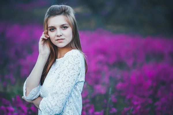 Bela noiva jovem no campo, mulher feliz apreciando flores . — Fotografia de Stock