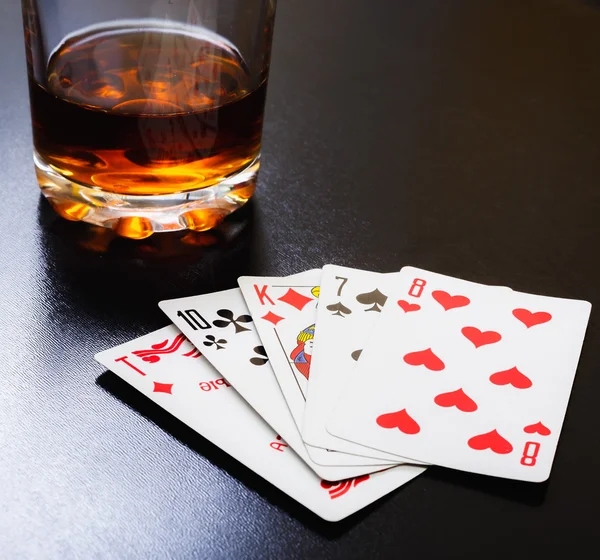 Un verre de whisky et des cartes à jouer sur un bureau noir sur la table en bois. Vue d'angle, cartes d'identité — Photo