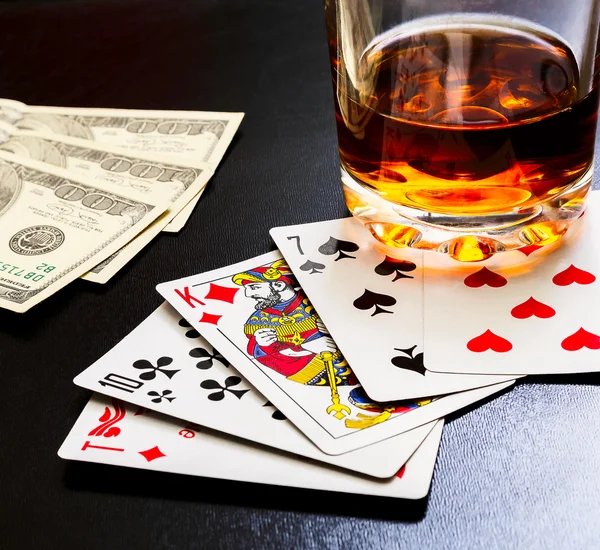 Bardak viski ve iskambil ve ahşap masa üzerinde siyah bir masa üzerine para.