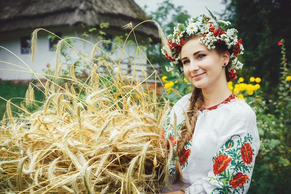 A young Ukrainian woman in traditional dress standing with hands in a haystack. — Stock Photo, Image