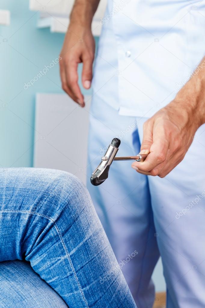 Neurologist checks reflexes hammering knee. The doctor examines the