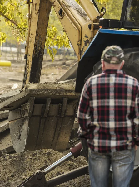 Werken graafmachine trekker graven van een greppel. — Stockfoto