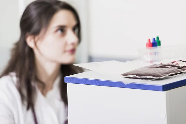 Médico mulher sentada a uma mesa em um casaco branco — Fotografia de Stock