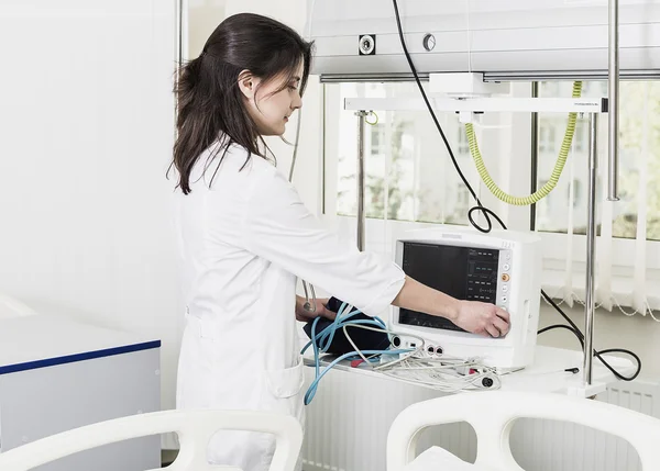 Girl Doctor in a white coat adjusts clinical equipment and monitor — Stock Photo, Image