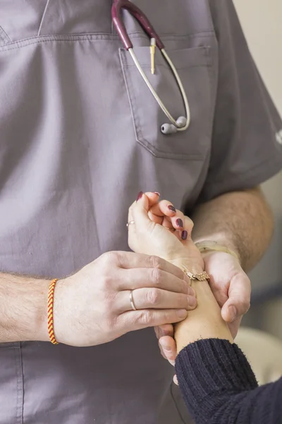 Medico barbuto con gli occhiali controlla il polso del paziente — Foto Stock