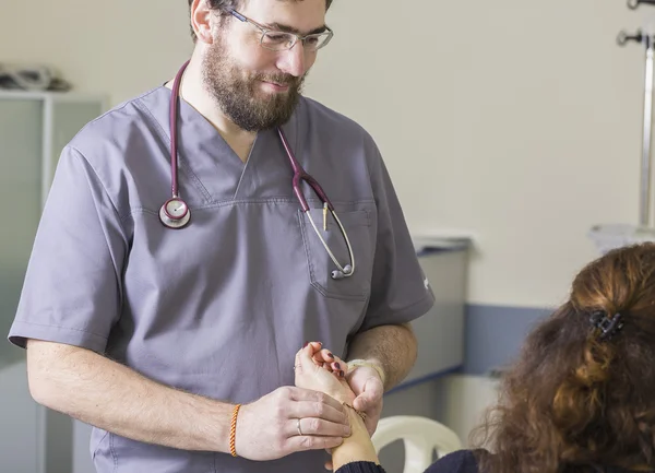 Médico barbudo usando óculos verifica o pulso do paciente — Fotografia de Stock