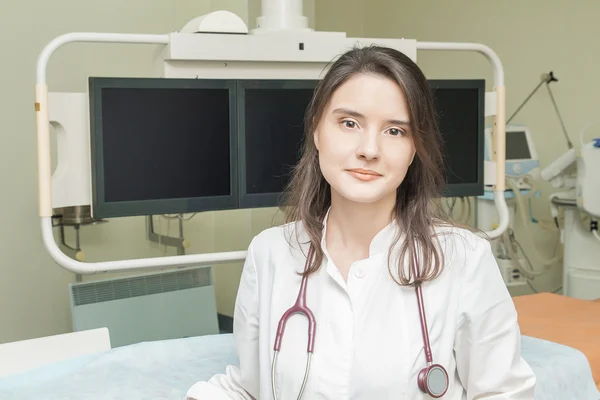 Meisje arts in een witte vacht past klinische apparatuur en monitor — Stockfoto