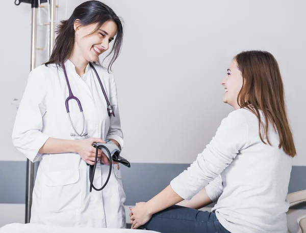 beautiful girl doctor in a white coat checks the blood pressure in the girl on the bed