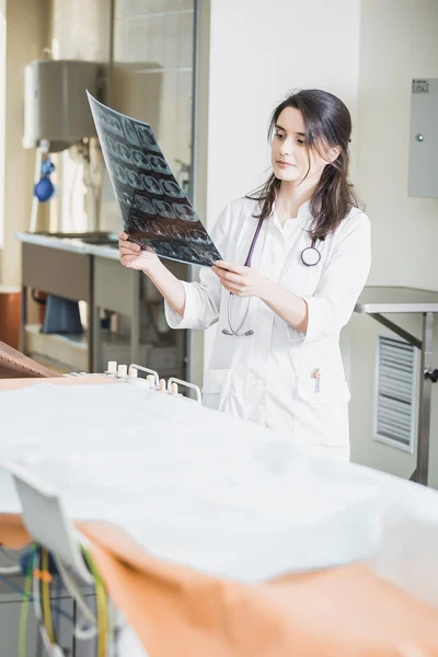 Mooi meisje arts in een witte vacht onderzoekt X-ray foto van de patiënt om het probleem te identificeren. Professionele gesprek, raadpleging van artsen. De werkzaamheden van de conferentie. — Stockfoto