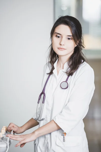 Mooi meisje arts in een witte vacht staande in het ziekenhuis glimlachen — Stockfoto