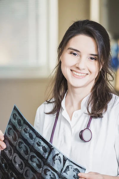 Mooi meisje arts in een witte vacht onderzoekt X-ray foto van de patiënt om het probleem te identificeren. Professionele gesprek, raadpleging van artsen. De werkzaamheden van de conferentie. — Stockfoto