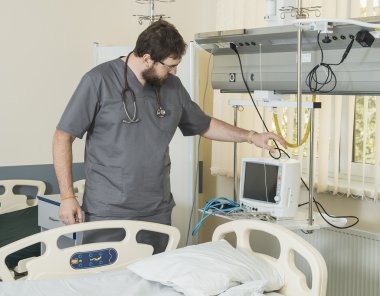 gözlük ve gri bir elbise giyen sakallı doktor hastane ekipmanları ile çalışır