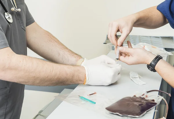 Medico con assistente che inietta sangue nella siringa — Foto Stock