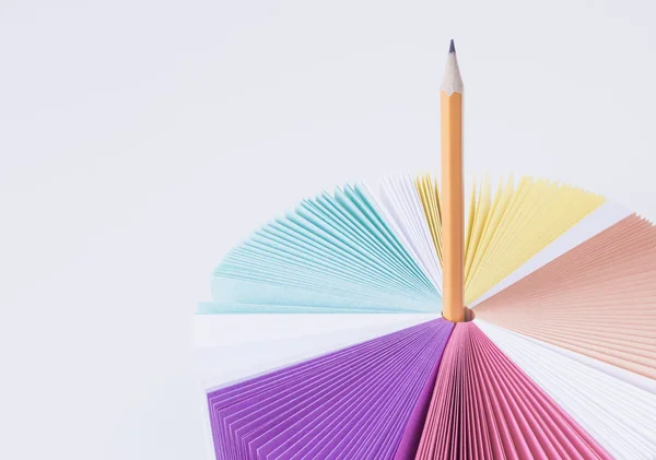 Papier coloré pour notes arc-en-ciel sur une table blanche. Fond blanc. Crayon orange . — Photo