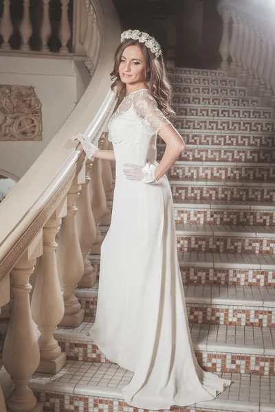 Krásná elegantní dívka v bílých šatech, stojící na vinobraní schodiště v zámku — Stock fotografie