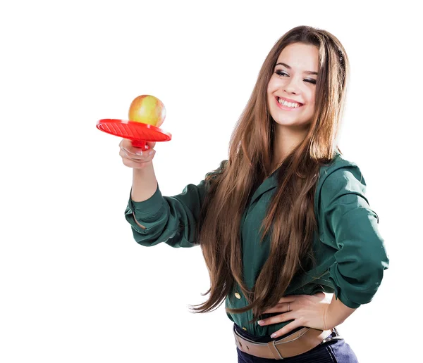 Όμορφη κοπέλα με μια Πράσινη μπλούζα κρατώντας ένα μήλο με ένα χαμογελαστό ρακέτα τένις. Apple θέλει να χτυπήσει την ρακέτα. απομόνωση — Φωτογραφία Αρχείου