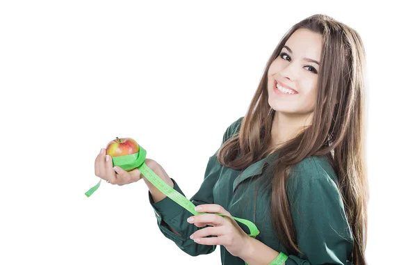 Joven hermosa chica con el pelo oscuro aislado sobre un fondo blanco sosteniendo una manzana con una cinta métrica. — Foto de Stock
