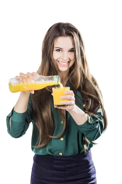 Hermosa chica con el pelo oscuro que vierte de una botella en un vaso de jugo de naranja sobre un fondo blanco — Foto de Stock