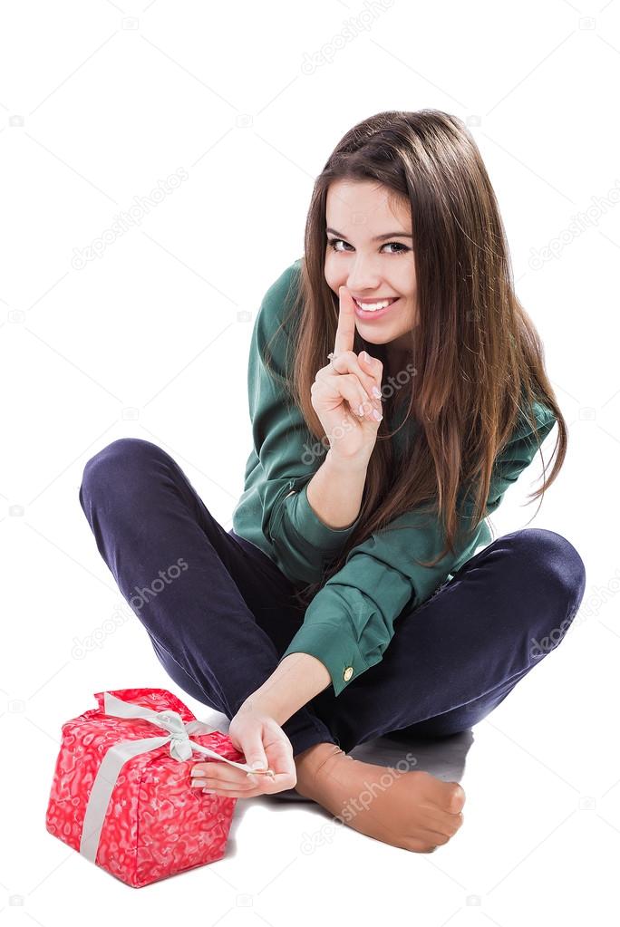 beautiful young girl sitting on a white background holding a box with a gift. Smiles.