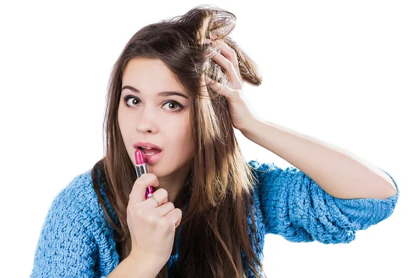 Beautiful young girl in a blue sweater standing on a white background and holding a red lipstick. Dyed lips. — Stock Photo, Image