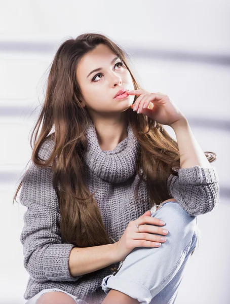 Menina bonita com cabelo escuro longo fotografado por uma grade preta, uma cadeira. Em um fundo branco . — Fotografia de Stock