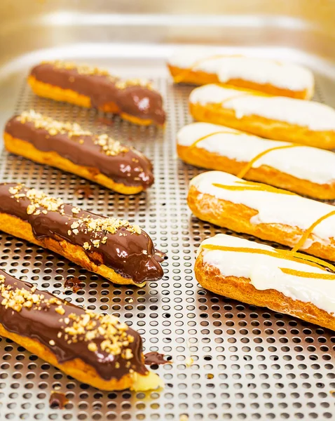 Pastry eclairs decorated with black and white chocolate and orange rind