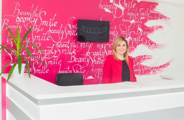 Portrait of smiling young woman with receptionist in dentist's office