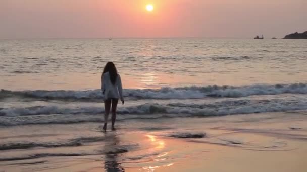 Mujer joven saltando en la playa al atardecer . — Vídeos de Stock