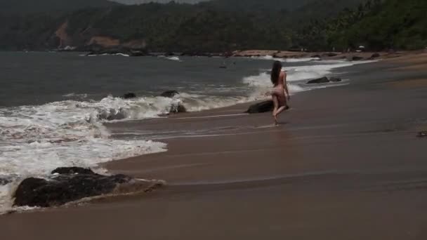 Donna che cammina sulla spiaggia con le onde . — Video Stock