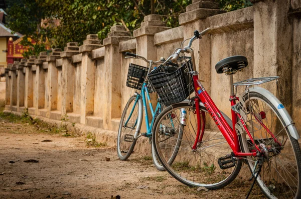 Bicicleta vermelha e azul em pé em uma parede na Ásia — Fotografia de Stock