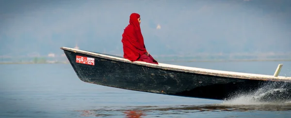 Monk in rood gewaad, zittend op een motorboot — Stockfoto