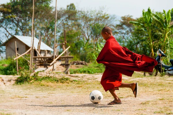 Monge em roupão vermelho jogando futebol — Fotografia de Stock