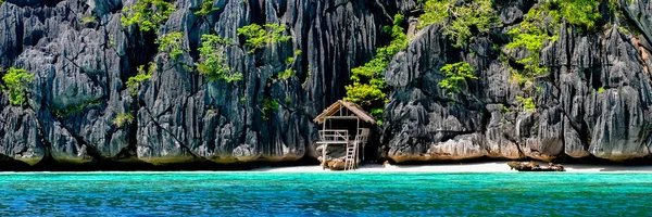 Einsames hölzernes Bambushaus auf Stelzen an einem kleinen versteckten Strand der felsigen Insel — Stockfoto