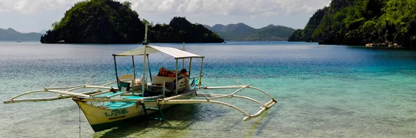 Tradiční dřevěné filipínský loď v modré laguny s průzračnou vodou na tropický ostrov — Stock fotografie