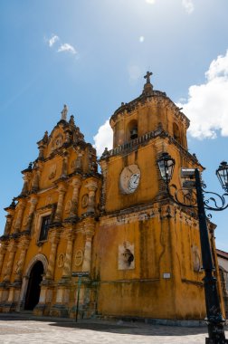 Beyaz saat ve mavi gökyüzü altında üstte bir çan ile sarı Kilisesi önünde eski latern