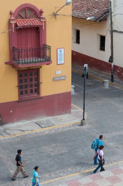 İnsanlar bir kırmızı sarı sömürge ev ve Leon köşede yanındaki sokakta yürürken, insanlar