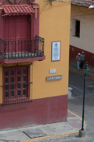 Pessoas Caminhando na rua ao lado de uma casa colonial amarela vermelha e canto em Leon — Fotografia de Stock