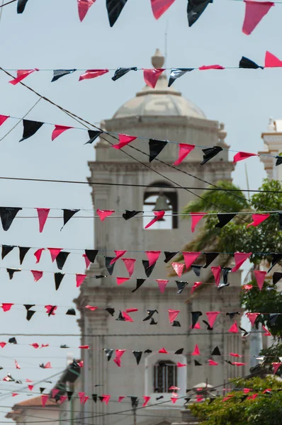 Plásticos triangulares vermelhos e pretos pendurados nas linhas em frente a uma grande igreja branca — Fotografia de Stock