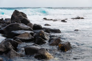 Siyah kaya taş sahil kaba Rüzgarlı deniz dalgaları ile önünde