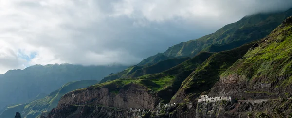 Nube de roca negra costa de piedra con casas y colina verde en la isla de Cabo Verde —  Fotos de Stock