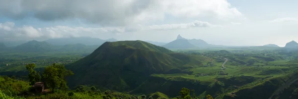 Vallée verte avec colline au milieu sous un ciel nuageux — Photo