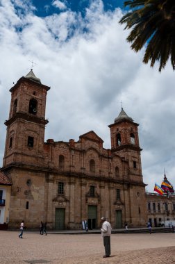 Yaşlı adam ile bulutlar mavi gökyüzü altında koloni bej taş Kilisesi önünde