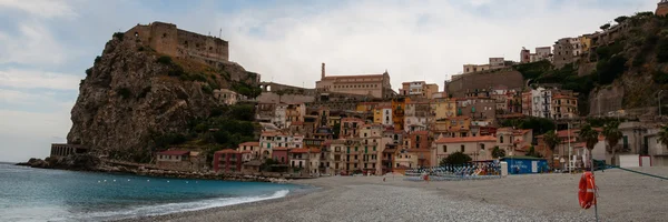 Playa de piedra y viejo pueblo italiano en el acantilado bajo el cielo azul — Foto de Stock