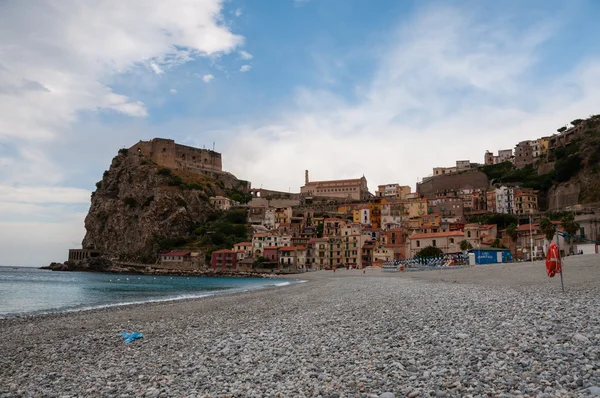 Praia de pedra e velha pequena cidade italiana em penhasco sob o céu azul — Fotografia de Stock