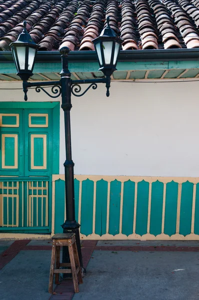 Lantern in front of green yellow colorful colonial house