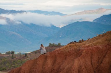 Büyük kırmızı kumtaşı kaya oluşumu yamaç sıcak kuru çöl Tatacoa, Huila içinde oturan kadın